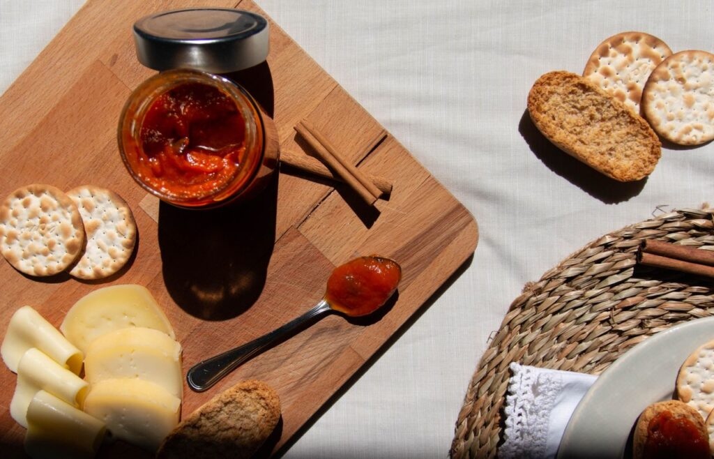Elegant charcuterie board with cheese, jam, and crackers on a wooden board in natural light.