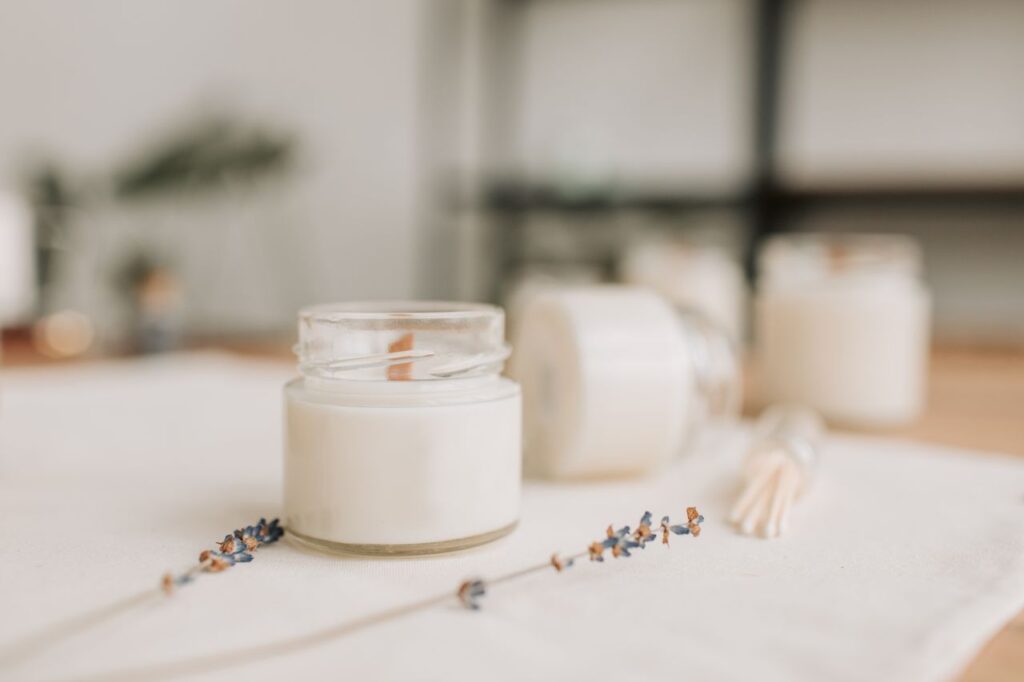 Warm and cozy candle setting with dried lavender and wax jar, perfect for a serene atmosphere.